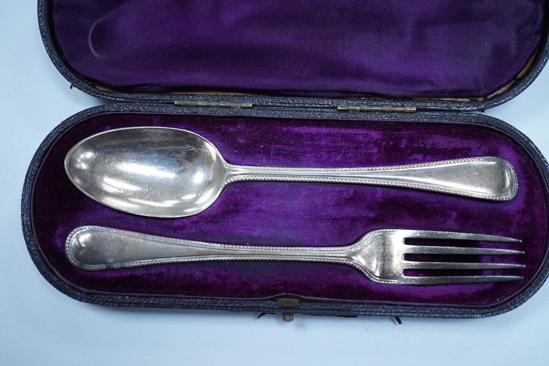 A pair of George V silver mounted dwarf candlesticks, Birmingham, 1920, height 86mm (a.f.), together with a cased Victorian silver beaded Old English pattern christening knife and fork, George Adams, London, 1881.